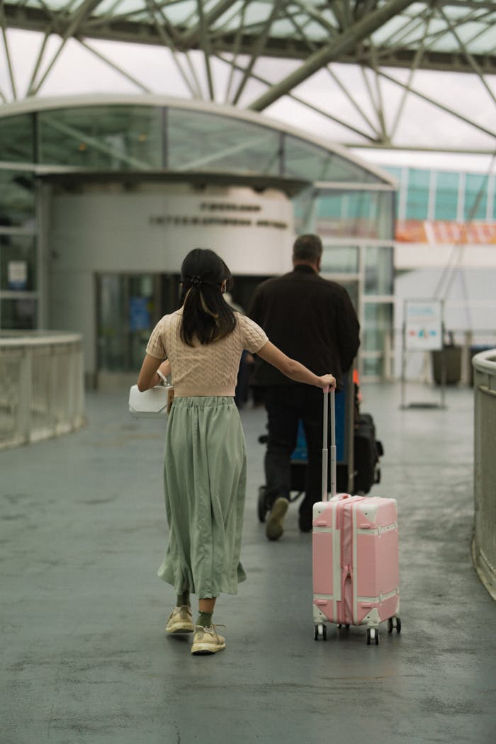 A man and woman with luggage entering an airport terminal, symbolizing travel and exploration.