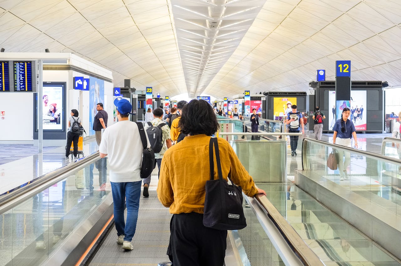 who-we-are Passengers walking through a modern airport terminal in Hong Kong, capturing the essence of travel.